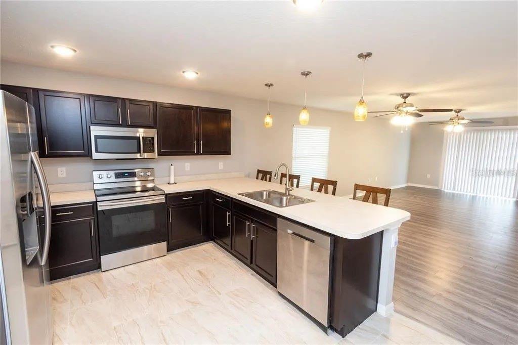 A kitchen with dark cabinets, stainless steel appliances, and a light-colored island countertop — 307 NW 8TH STREET, MULBERRY, FL