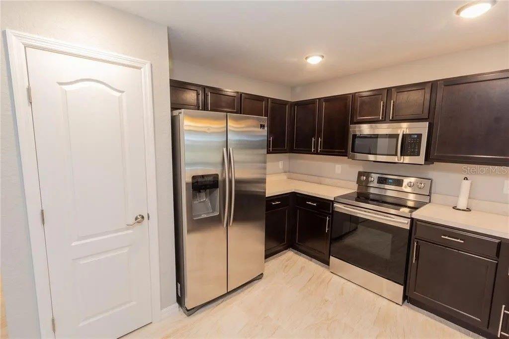 A kitchen features dark wood cabinets, stainless steel appliances, and light-colored countertops — 307 NW 8TH STREET, MULBERRY, FL
