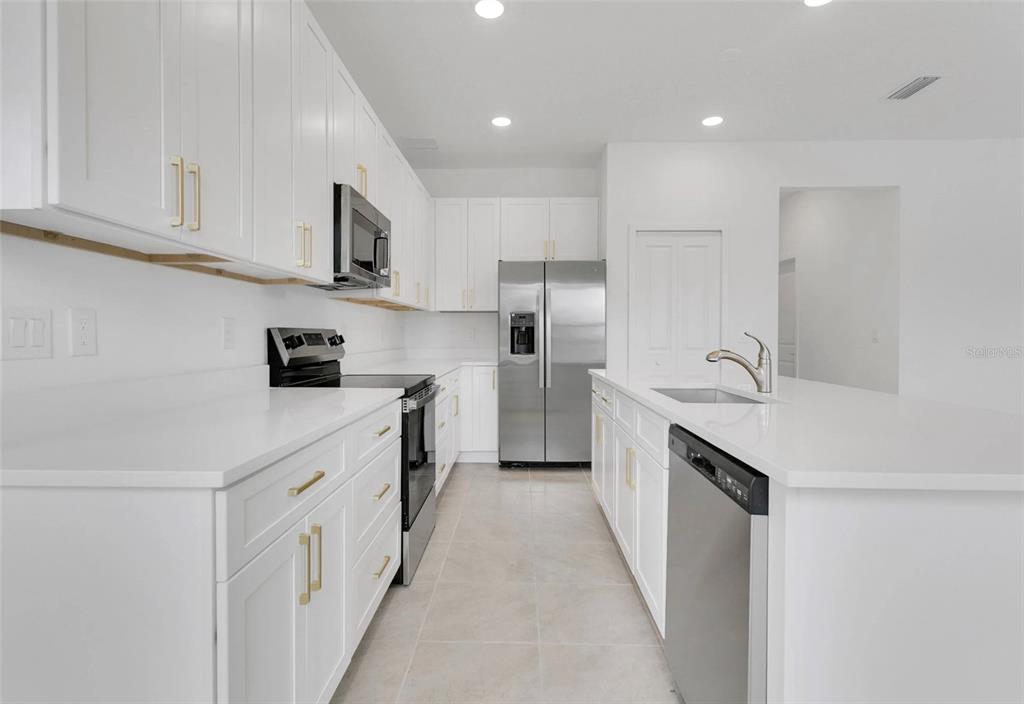 A modern kitchen features white cabinets, stainless steel appliances, and a central island with sink — 292 ELENA LAVIN CIRCLE, ORLANDO, FL