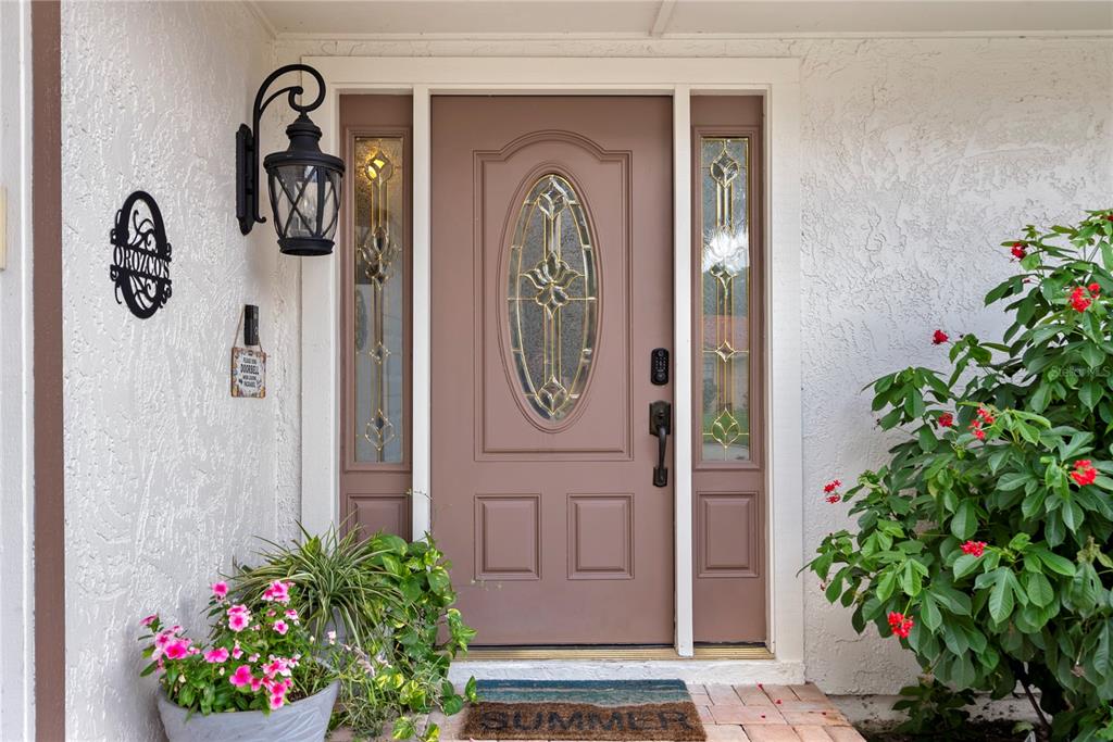 A brown front door with a glass oval insert is flanked by two sidelight windows — 655 NIGHTHAWK CIRCLE, WINTER SPRINGS, FL