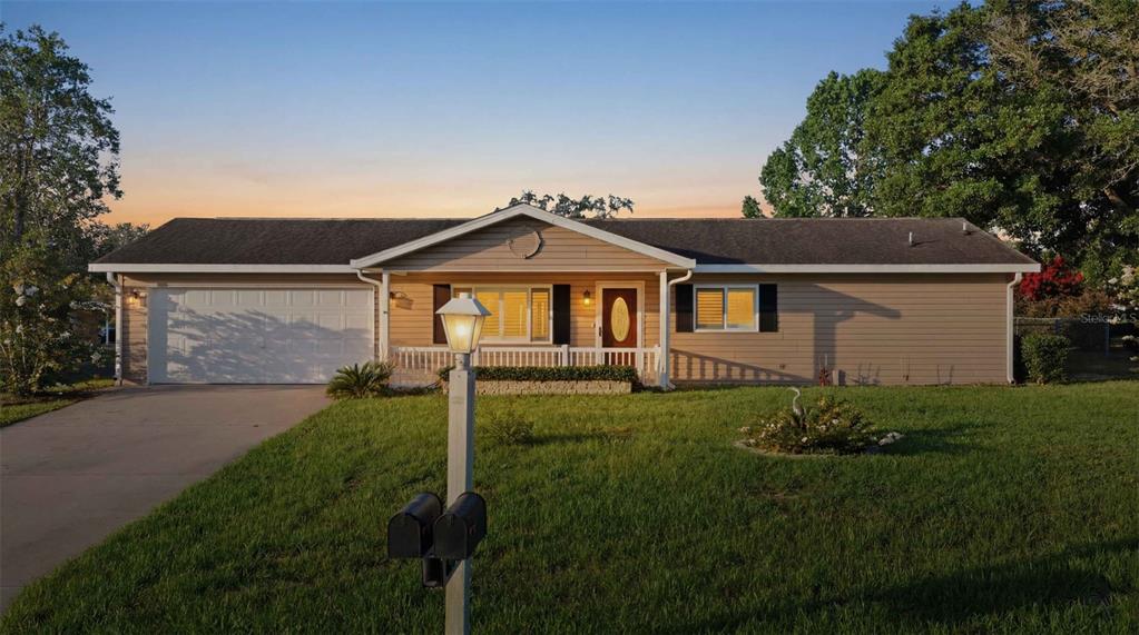 A single-story house with tan siding, a white garage, and a front porch at sunset — 6274 SW 106TH PLACE, OCALA, FL