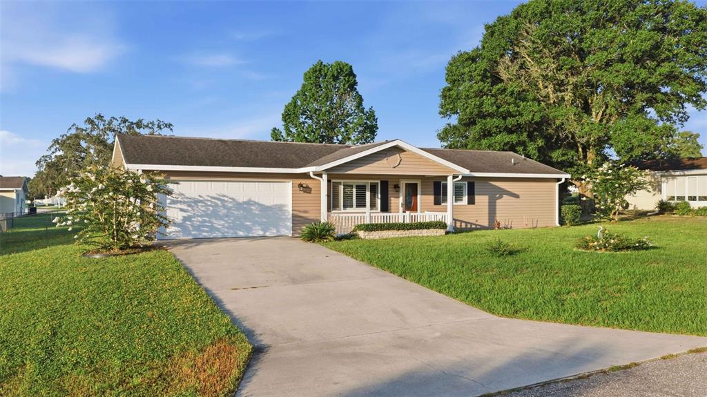 A single-story house with tan siding, a white garage door, and a concrete driveway — 6274 SW 106TH PLACE, OCALA, FL