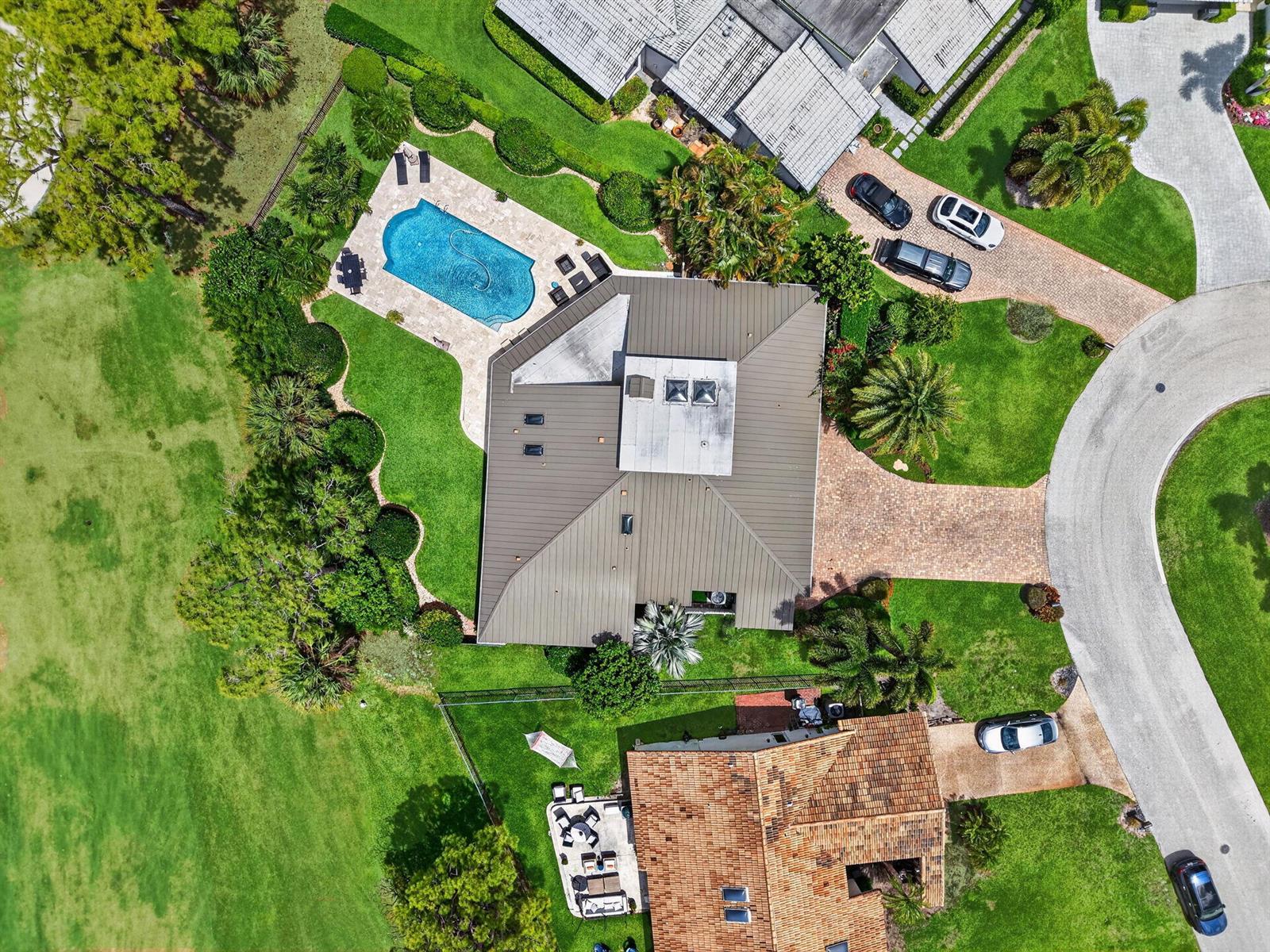 Aerial view of a residential property featuring a swimming pool, metal roof, and landscaped yard — 706 Foxpointe Circle, Delray Beach FL 33445, DELRAY BEACH, FL