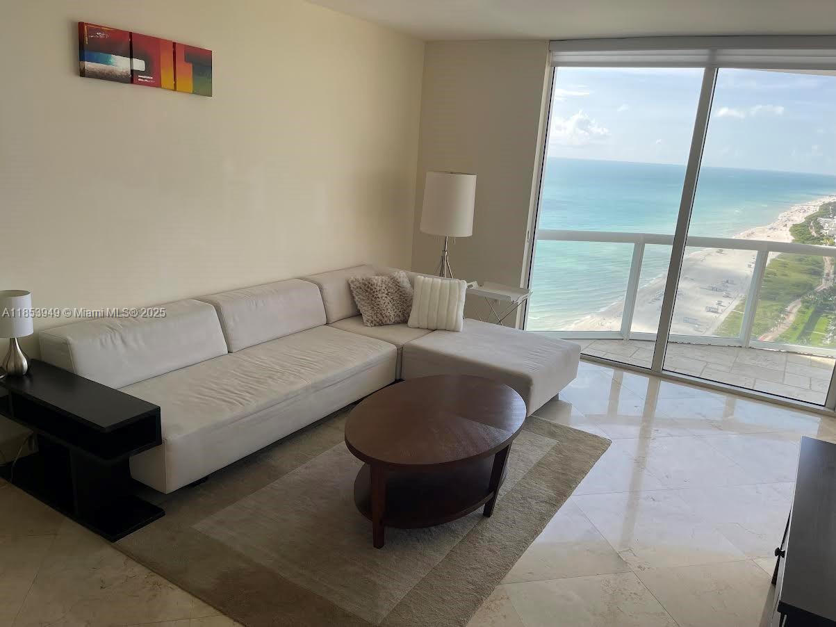 A living room features a white sectional sofa, a coffee table, and floor-to-ceiling ocean views — 6365 Collins Ave # 3404, Miami Beach FL 33141, MIAMI BEACH, FL