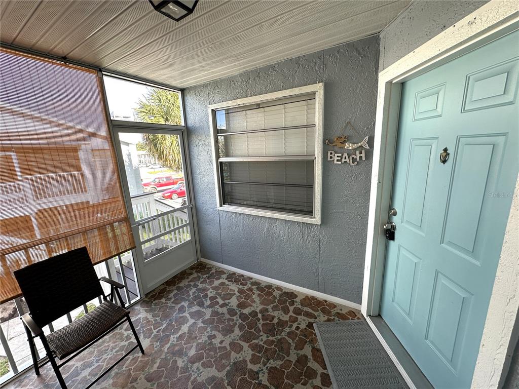 A covered porch features a light blue door, a window, and a patterned stone floor — 3821 59TH AVENUE W UNIT 3821, BRADENTON, FL