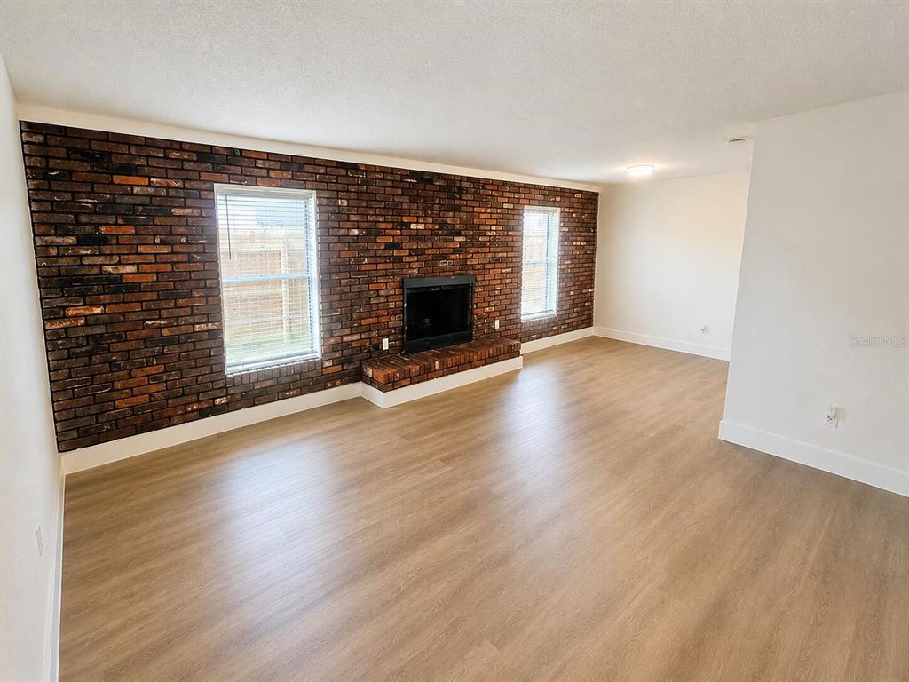 A living room features a brick accent wall with a fireplace and light wood flooring — 372 IMPERIAL DRIVE, CASSELBERRY, FL