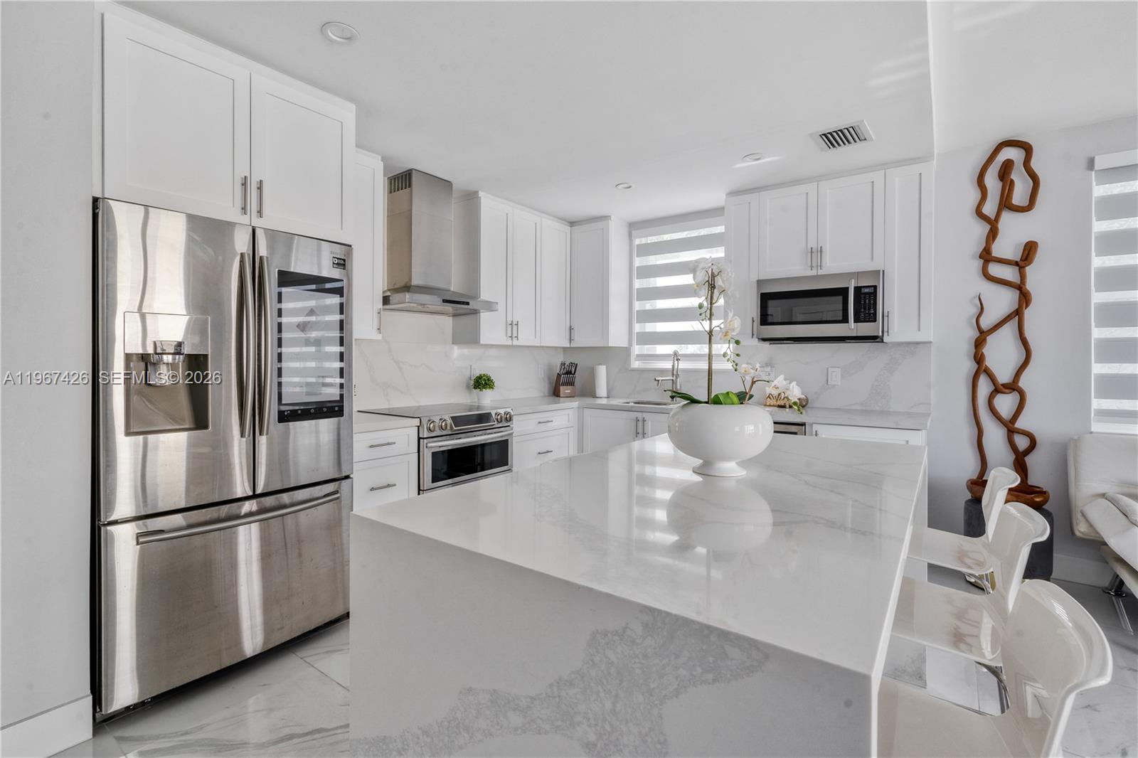 A modern white kitchen features a marble-topped island, stainless steel appliances, and white cabinetry — 94825 Overseas #178 # 178, Key Largo FL 33037, KEY LARGO, FL