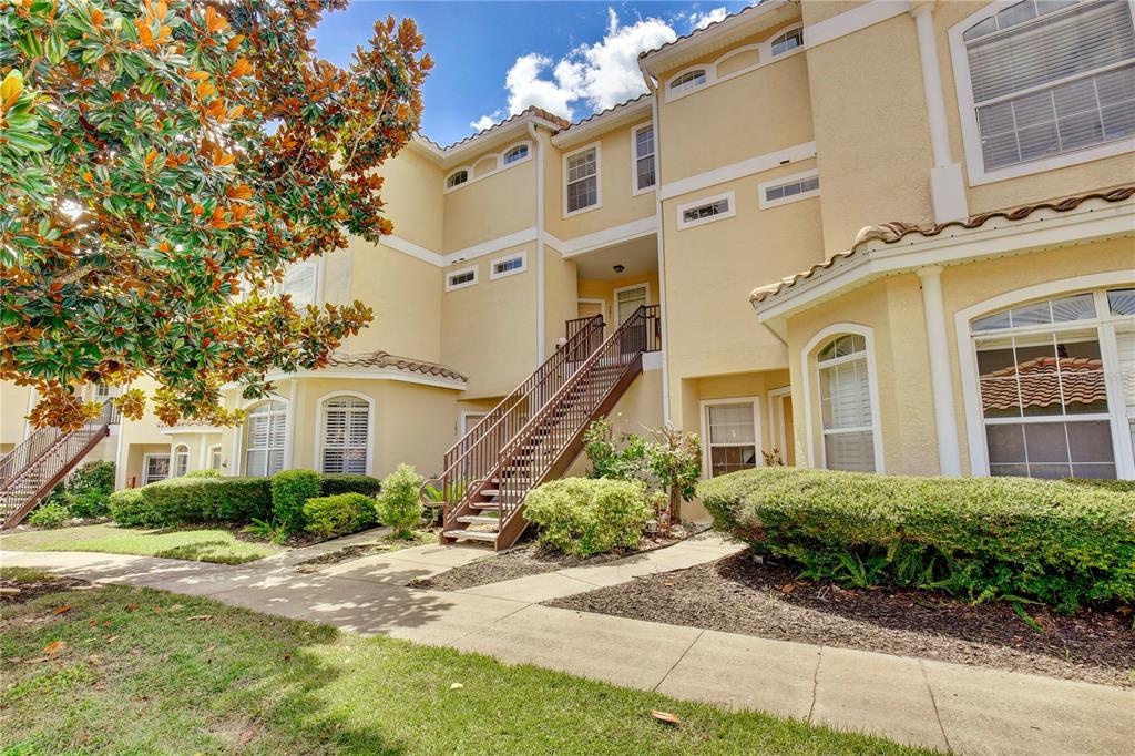 A tan multi-story apartment building exterior with an outdoor staircase and landscaped front yard — 696 SEABROOK COURT UNIT 202, ALTAMONTE SPRINGS, FL