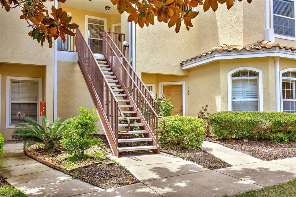 An exterior view of a two-story apartment building with a metal staircase and landscaping — 696 SEABROOK COURT UNIT 202, ALTAMONTE SPRINGS, FL