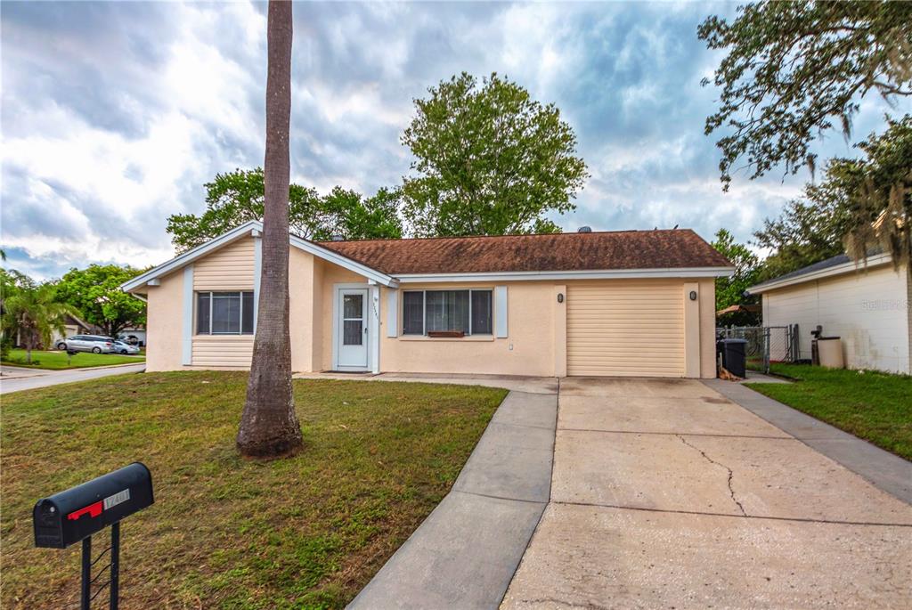 A single-story house with a beige exterior, a front-facing garage, and a palm tree — 12401 GUNSTOCK LANE, HUDSON, FL