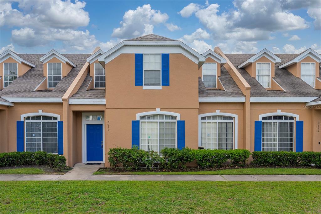 A two-story tan townhouse exterior features a blue front door and blue window shutters — 2035 ISLAND BROOK LANE, ORLANDO, FL