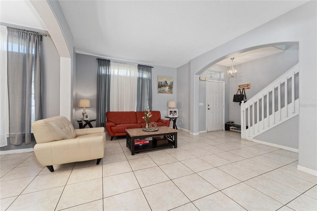 A living room features light tile floors, a red sofa, a beige armchair, and stairs — 2035 ISLAND BROOK LANE, ORLANDO, FL