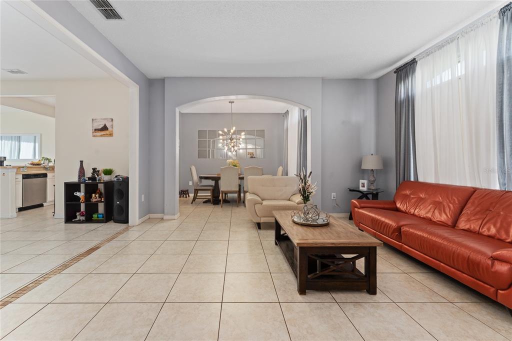 A living room with tile floors and a red leather sofa leads to a dining area — 2035 ISLAND BROOK LANE, ORLANDO, FL