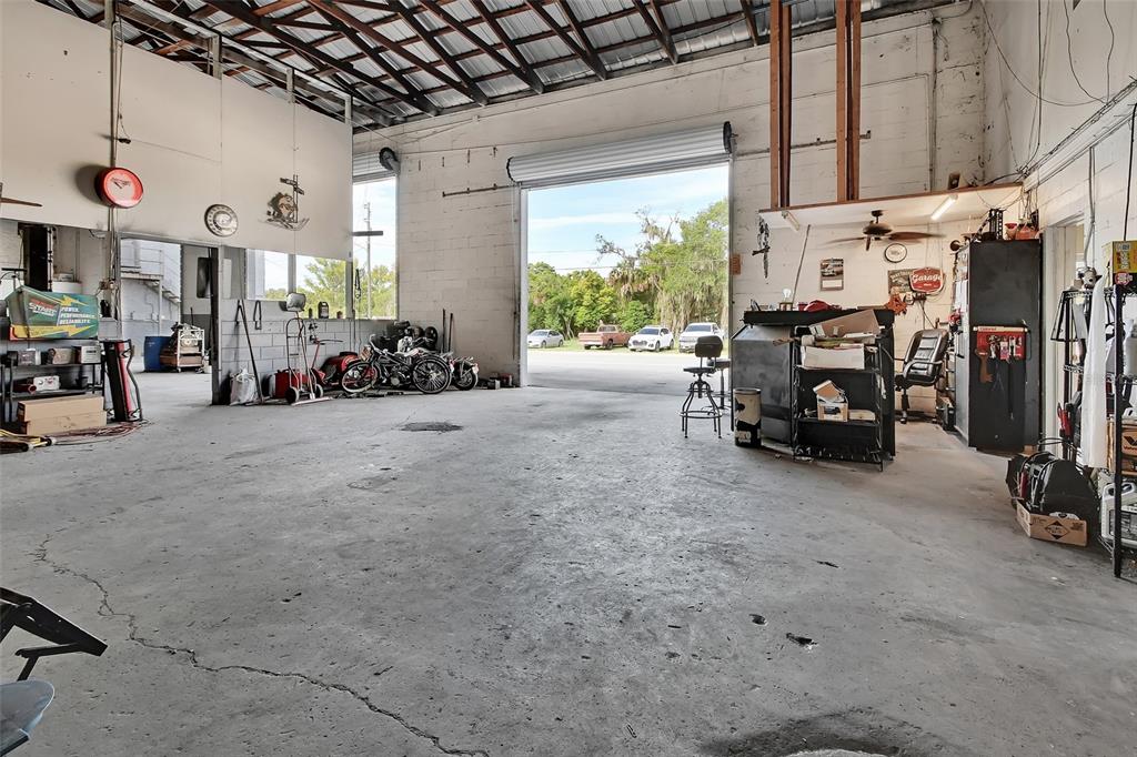 A spacious industrial garage features a concrete floor, high ceilings, and a large open bay — 309 S FLORIDA AVENUE, DELAND, FL