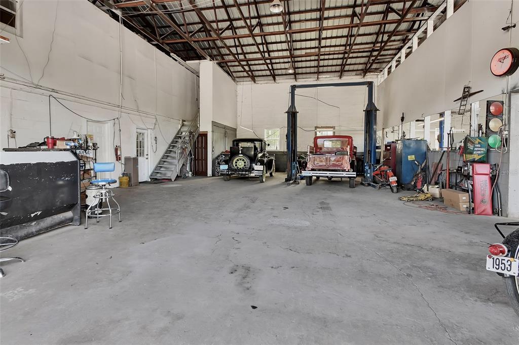 A spacious auto repair garage features a concrete floor, vehicle lift, and two vintage cars — 309 S FLORIDA AVENUE, DELAND, FL