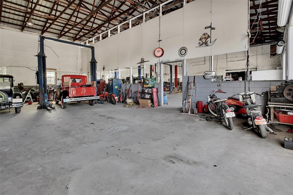 A spacious auto repair garage features a vehicle lift, concrete floors, and several vintage vehicles — 309 S FLORIDA AVENUE, DELAND, FL