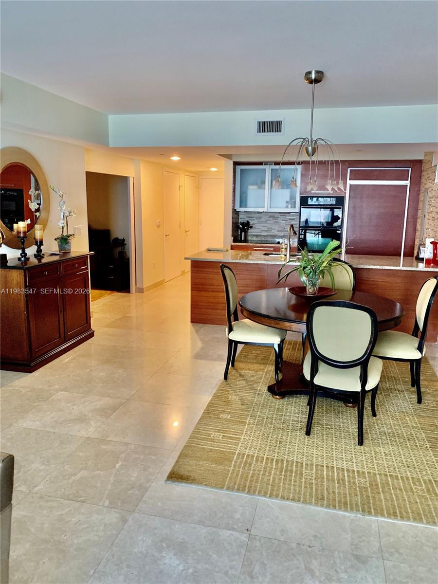 A dining area with a round table and chairs sits adjacent to a modern kitchen — 1830 S Ocean Dr # 2503, Hallandale Beach FL 33009, HALLANDALE BEACH, FL
