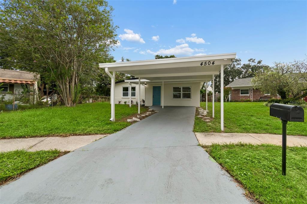 A single-story house with a white exterior, a carport, and a paved driveway — 4504 ASHMORE DRIVE, TAMPA, FL