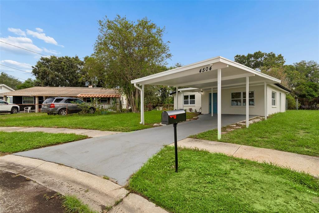 A single-story house with a white exterior, a carport, and a gray driveway — 4504 ASHMORE DRIVE, TAMPA, FL