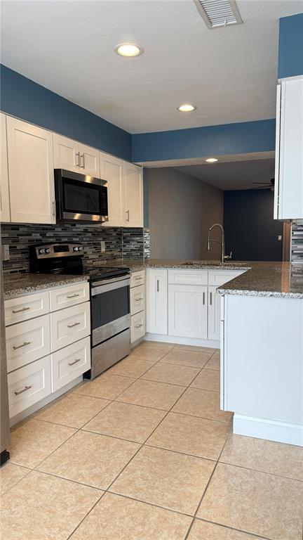 A kitchen features white cabinets, stainless steel appliances, granite countertops, and blue wall accents — 505 SUN RIDGE PLACE UNIT 122, ALTAMONTE SPRINGS, FL