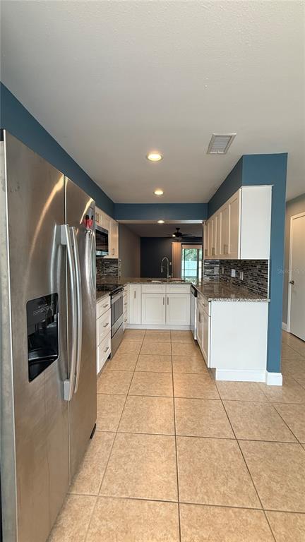 A kitchen features white cabinets, granite countertops, stainless steel appliances, and blue accent walls — 505 SUN RIDGE PLACE UNIT 122, ALTAMONTE SPRINGS, FL