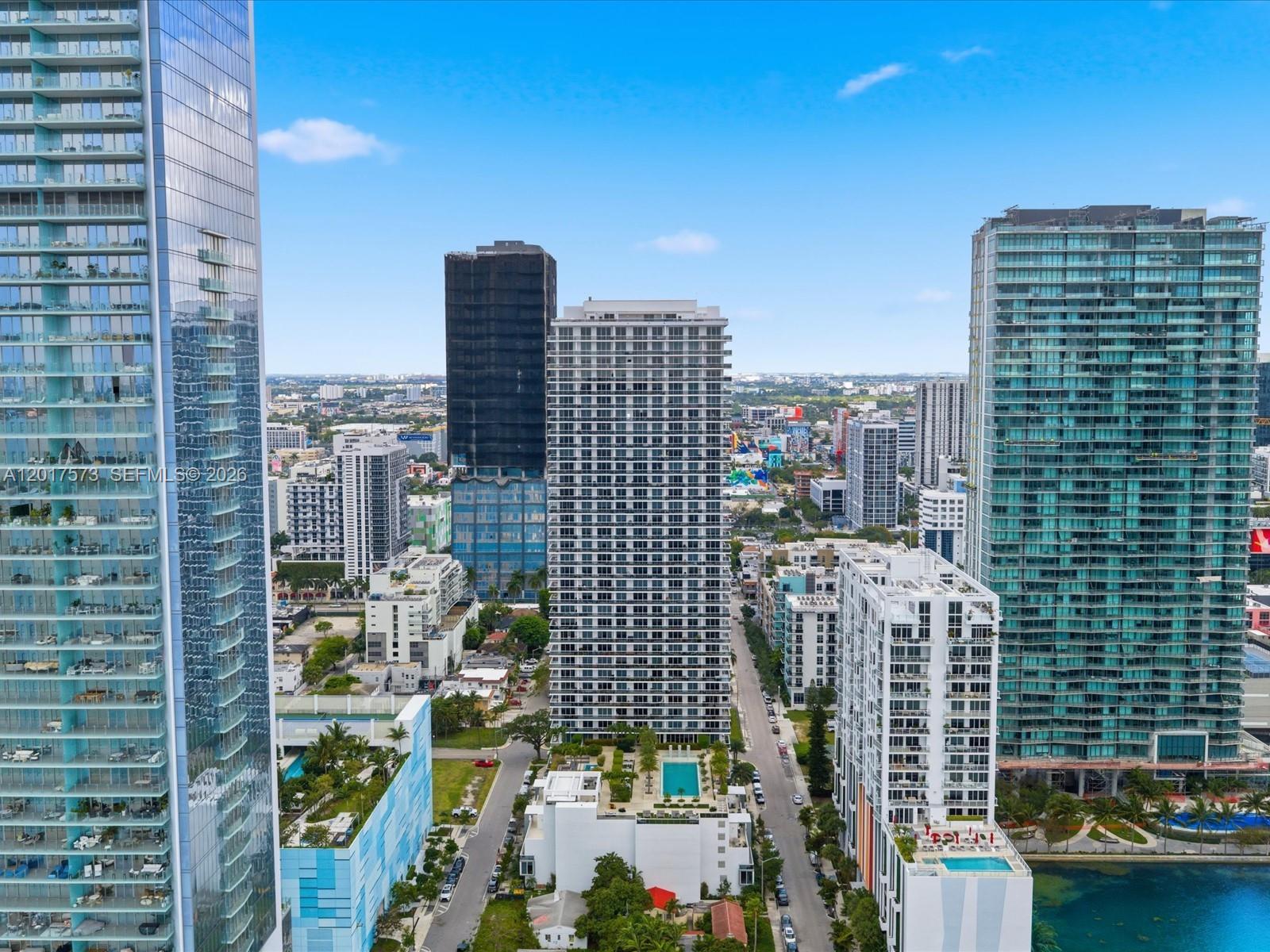 An aerial view shows several tall modern residential towers surrounding a street and swimming pools — 600 NE 27th St, Miami FL 33137, MIAMI, FL