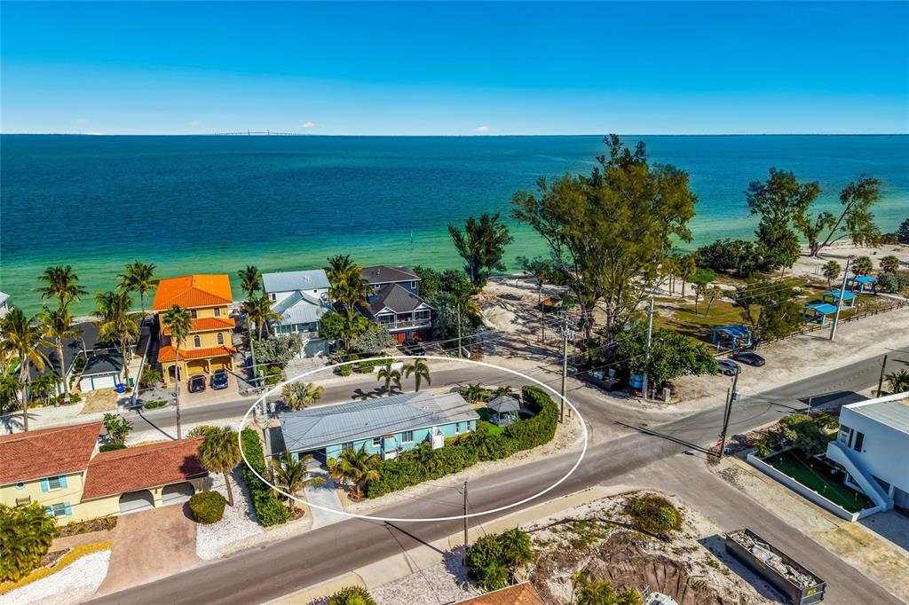 An aerial view shows a light blue house with a metal roof near the ocean — 912 N SHORE DRIVE, ANNA MARIA, FL