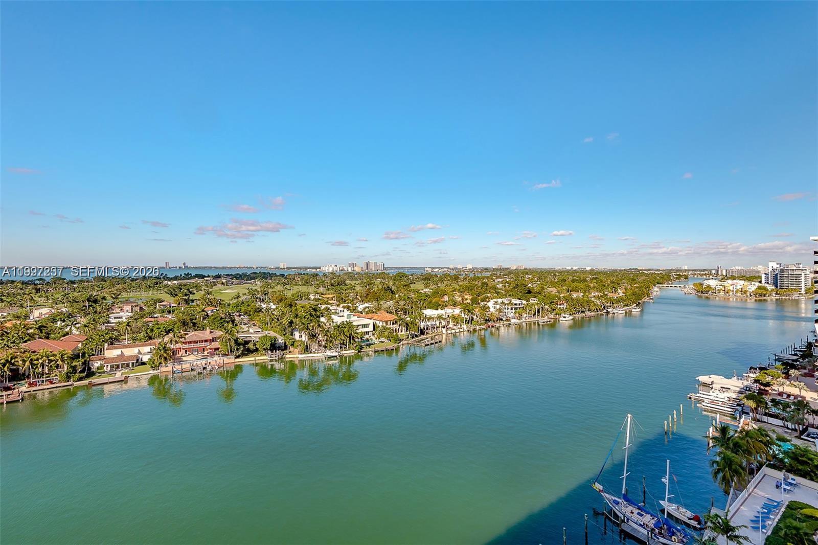 An elevated view of a waterway lined with houses, docks, and boats under a blue sky — 5600 Collins Ave # 16N, Miami Beach FL 33140, MIAMI BEACH, FL