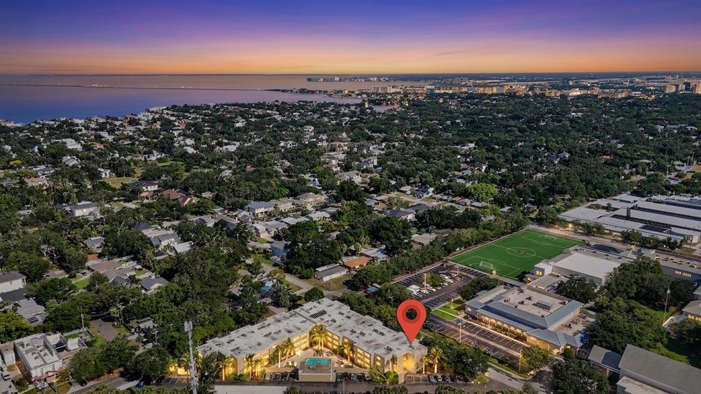 An aerial view shows a multi-story apartment building with a pool and a nearby soccer field — 2302 S MANHATTAN AVENUE UNIT 214, TAMPA, FL