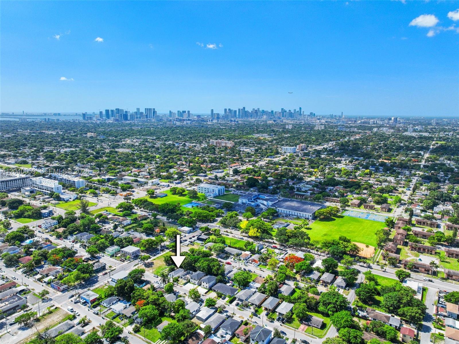 An aerial view shows a residential neighborhood with a white arrow pointing to a house — 1820 NW 63rd St, Miami FL 33147, MIAMI, FL