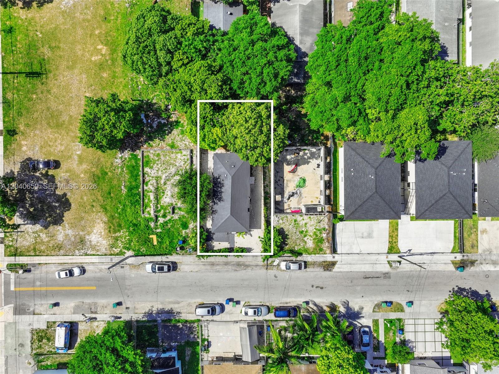 An aerial view shows a rectangular lot with a house surrounded by trees and grass — 1820 NW 63rd St, Miami FL 33147, MIAMI, FL