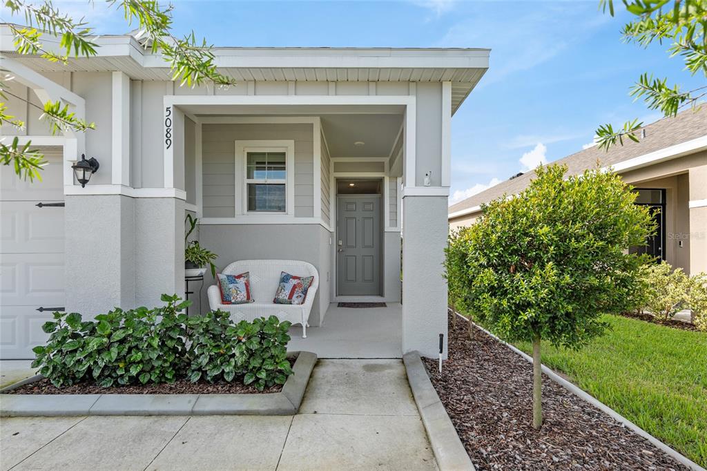 An entryway features a white front door, two interior doors, and gray walls with wainscoting — 5089 STOKES WAY, WILDWOOD, FL