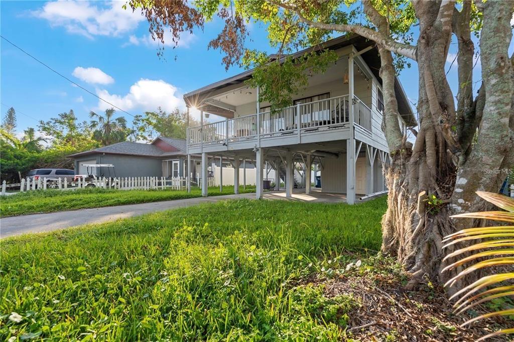 An elevated house with a large wooden deck stands above a concrete parking area — 1244 31ST AVENUE E, BRADENTON, FL