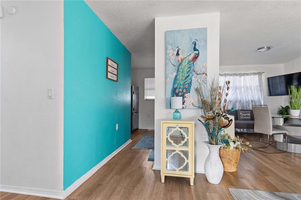 A bright teal accent wall leads to a dining area featuring a peacock wall art piece — 1244 31ST AVENUE E, BRADENTON, FL