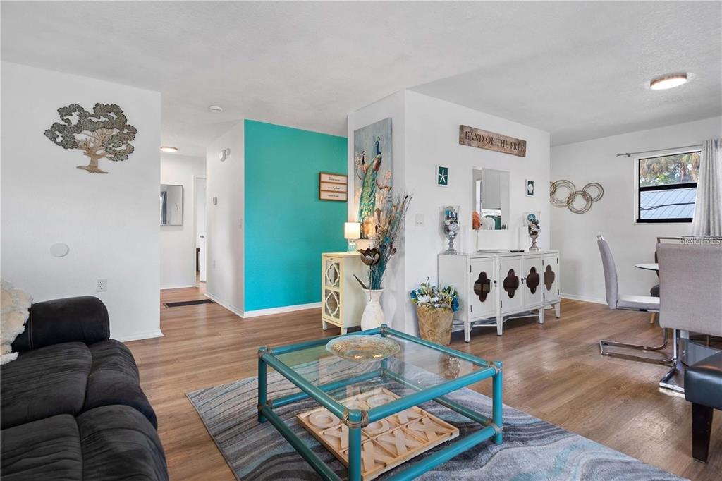 A living room with wood-look flooring, a teal accent wall, and a glass coffee table — 1244 31ST AVENUE E, BRADENTON, FL