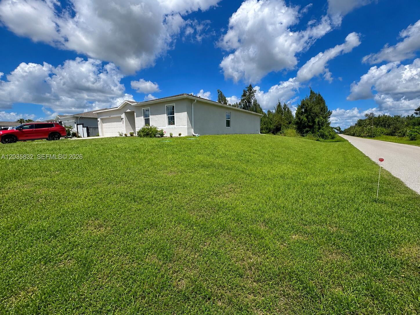 A light-colored single-story house sits on a large grassy lot next to a road — 26484 View Dr, Punta Gorda FL 33983, PUNTA GORDA, FL