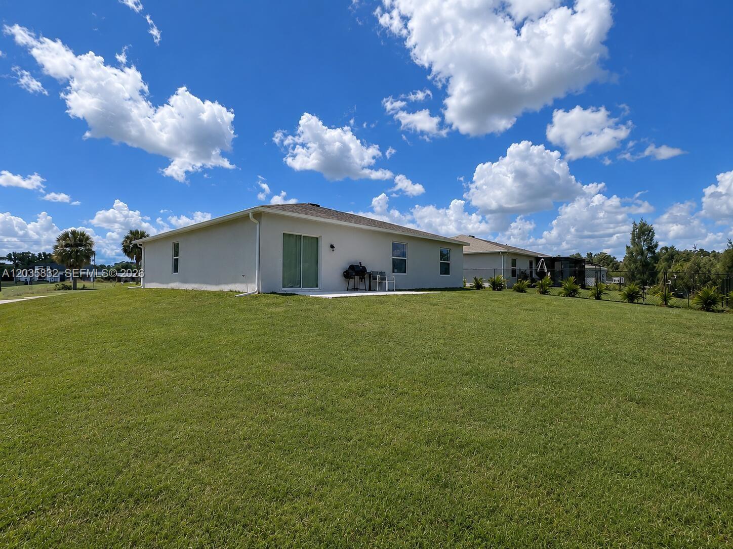 The exterior of a single-story house features a grassy backyard, a patio, and a fence — 26484 View Dr, Punta Gorda FL 33983, PUNTA GORDA, FL