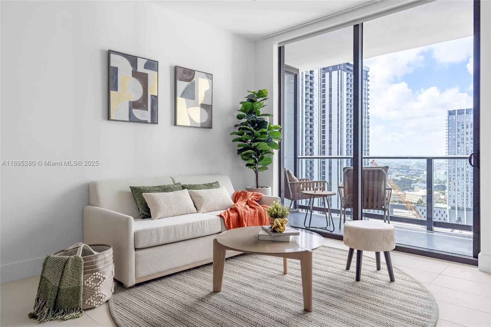 A modern living room features a beige sofa, round coffee table, and a balcony view — 159 NE 6TH ST # 2704, Miami FL 33132, MIAMI, FL