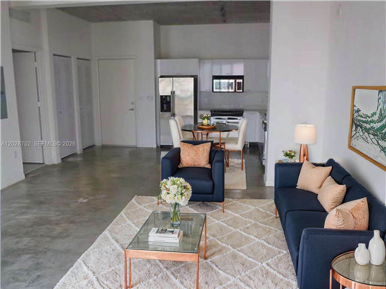 A living room with a navy sofa and armchair sits on a textured rug — 234 NE 3rd St # 1208, Miami FL 33132, MIAMI, FL