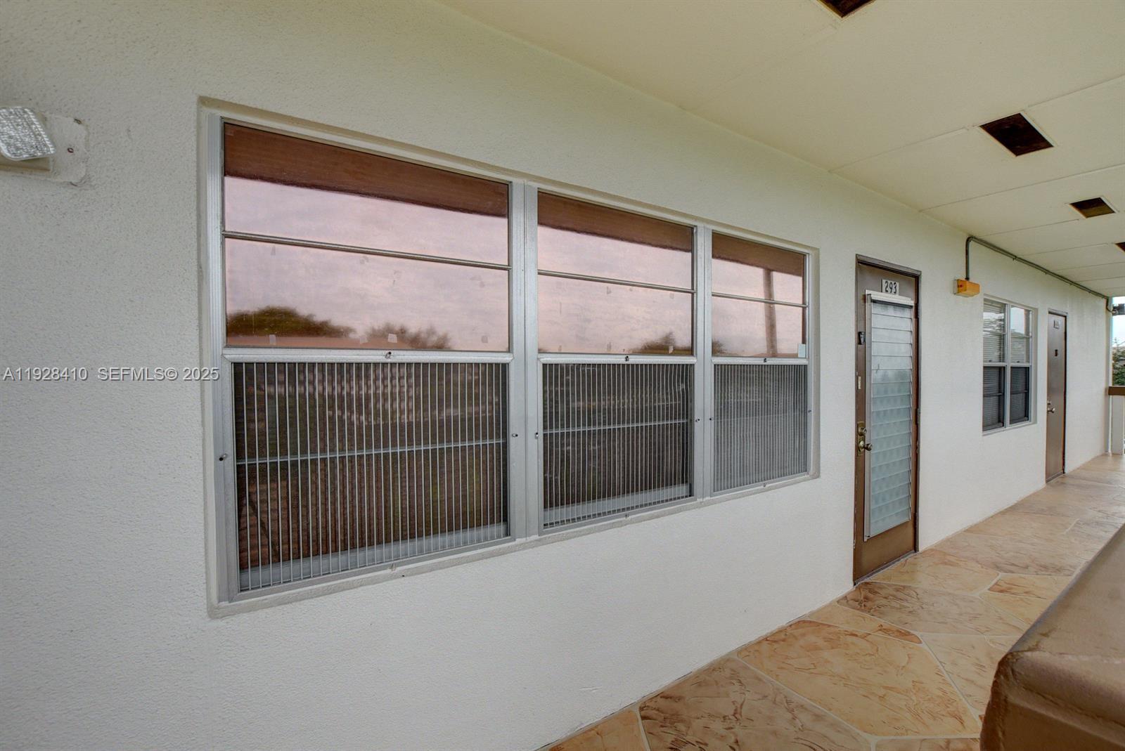An exterior view shows a walkway with a large window and a brown door — 293 Mansfield G # 293, Boca Raton FL 33434, BOCA RATON, FL