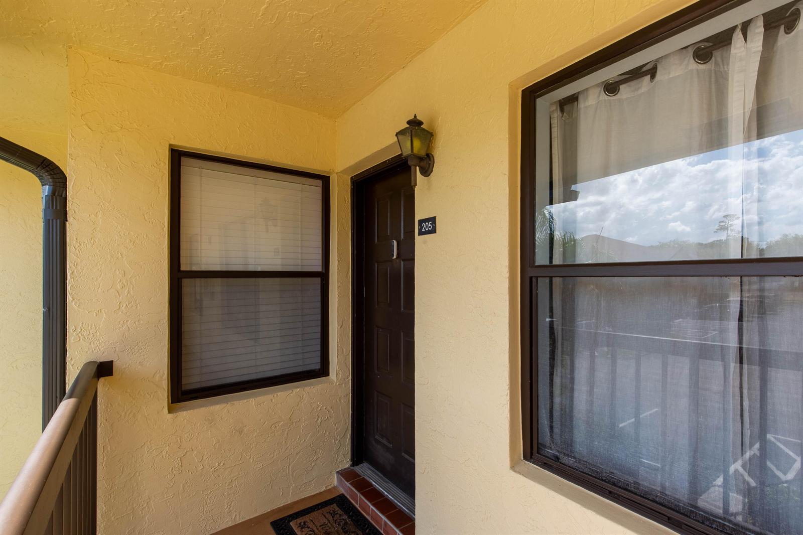 The exterior entrance of a residential unit features a brown door numbered 205 — 4715 Lucerne Lakes Boulevard E # 205, FL 33467, FL