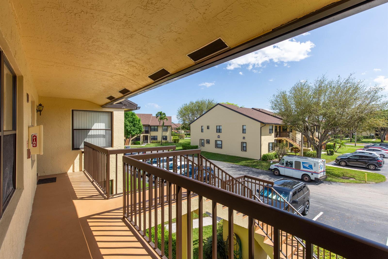An elevated apartment balcony overlooks a parking lot with a mail truck and residential buildings — 4715 Lucerne Lakes Boulevard E # 205, FL 33467, FL