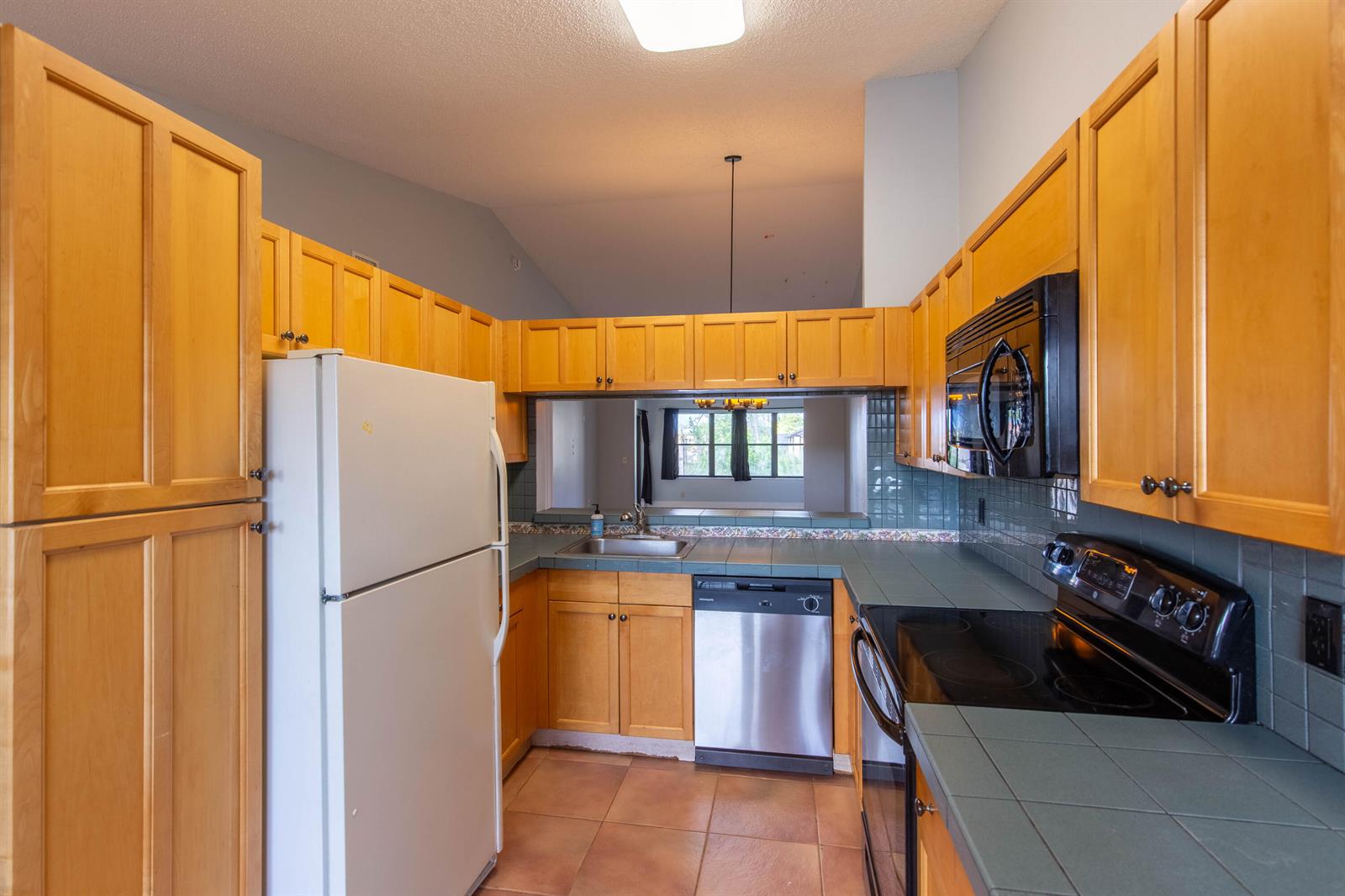 A kitchen features light wood cabinets, teal tile countertops, and stainless steel appliances — 4715 Lucerne Lakes Boulevard E # 205, FL 33467, FL