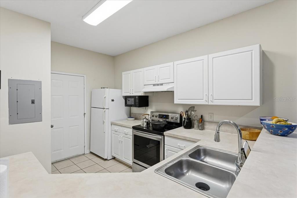 A kitchen features white cabinets, stainless steel appliances, a double sink, and tiled flooring — 13200 W NEWBERRY ROAD UNIT 86, NEWBERRY, FL