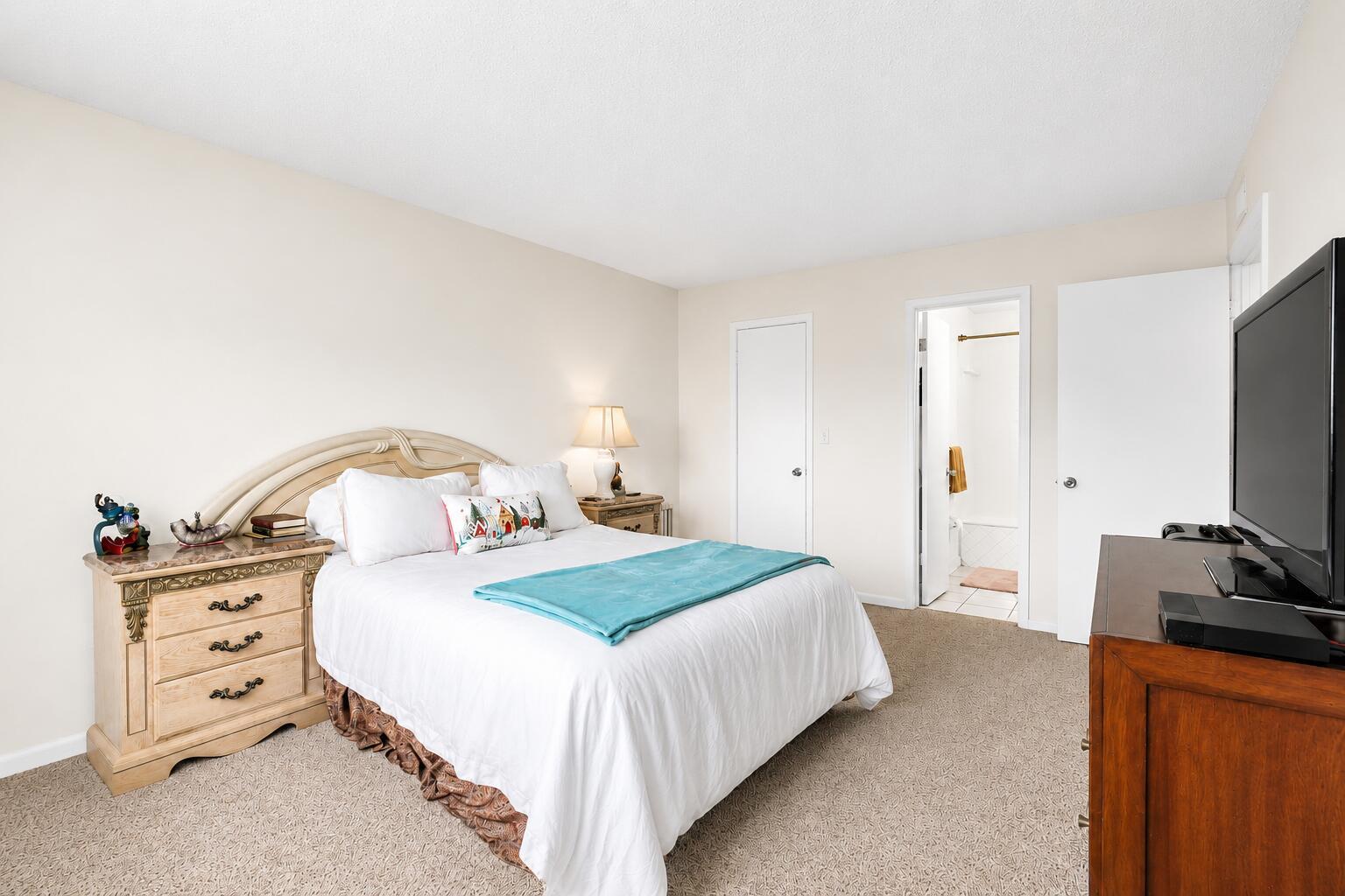 A bedroom features a bed with a teal throw, a nightstand, and an attached bathroom — 6507 Winfield Boulevard, Margate FL 33063, MARGATE, FL