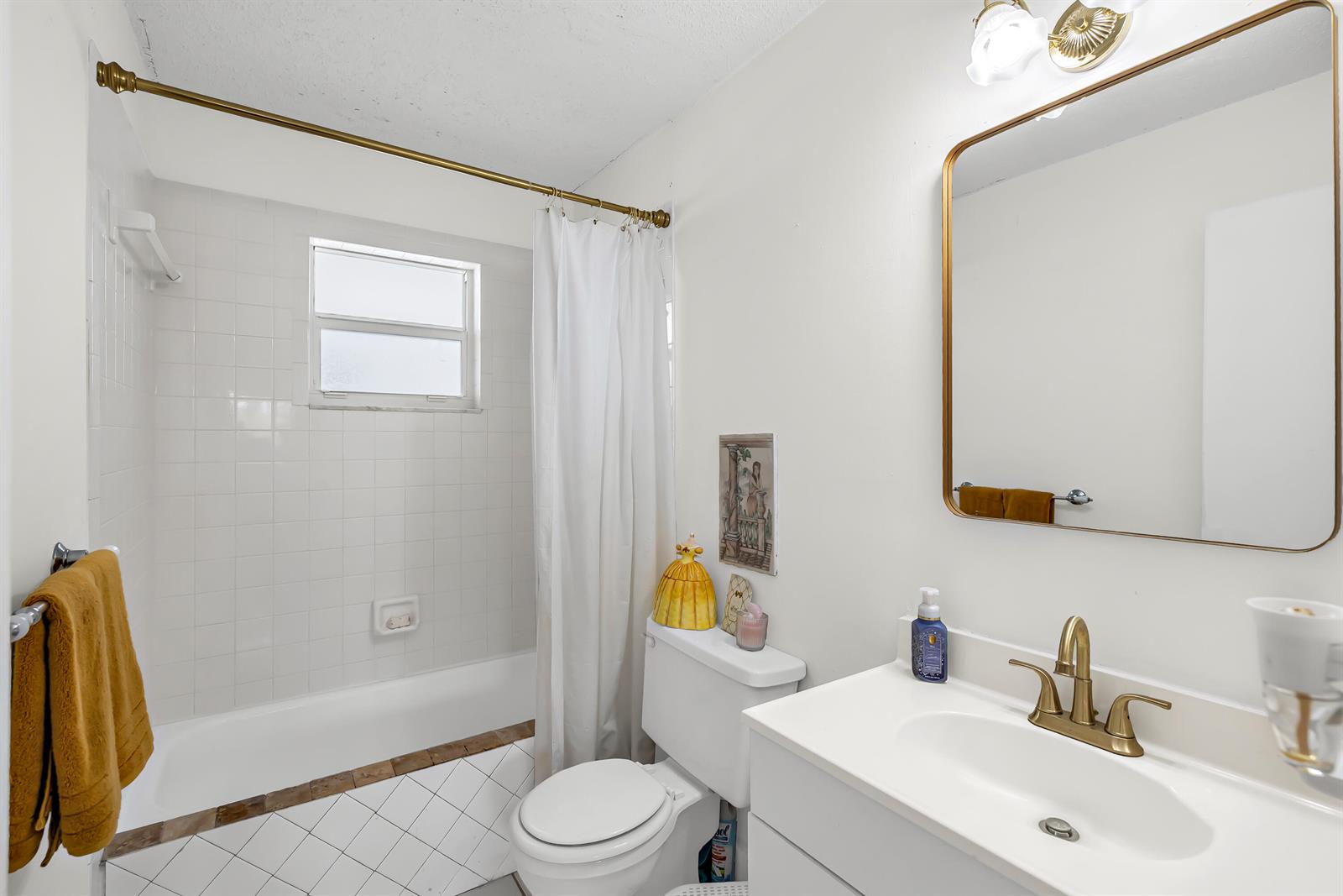 A bathroom features a white vanity, a toilet, and a shower-tub combo with white tiles — 6507 Winfield Boulevard, Margate FL 33063, MARGATE, FL