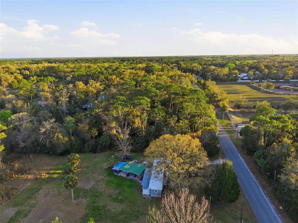 An aerial view shows a house with a carport on a large, wooded rural lot — 2085 S STONEBROOK DRIVE, HOMOSASSA, FL