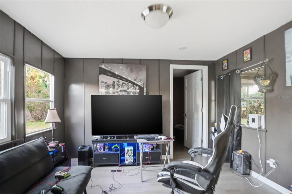 A gaming room features dark gray paneled walls, a large television, and a gaming chair — 2085 S STONEBROOK DRIVE, HOMOSASSA, FL
