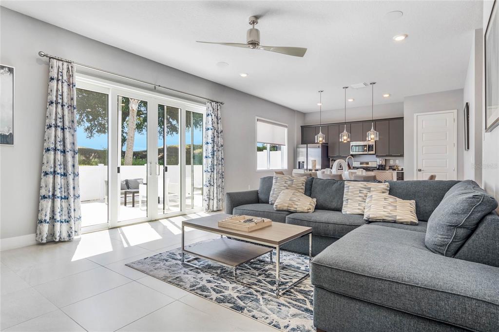A living room with a gray sectional sofa, coffee table, and sliding glass patio doors — 7770 SANDY RIDGE DRIVE UNIT 112, REUNION, FL