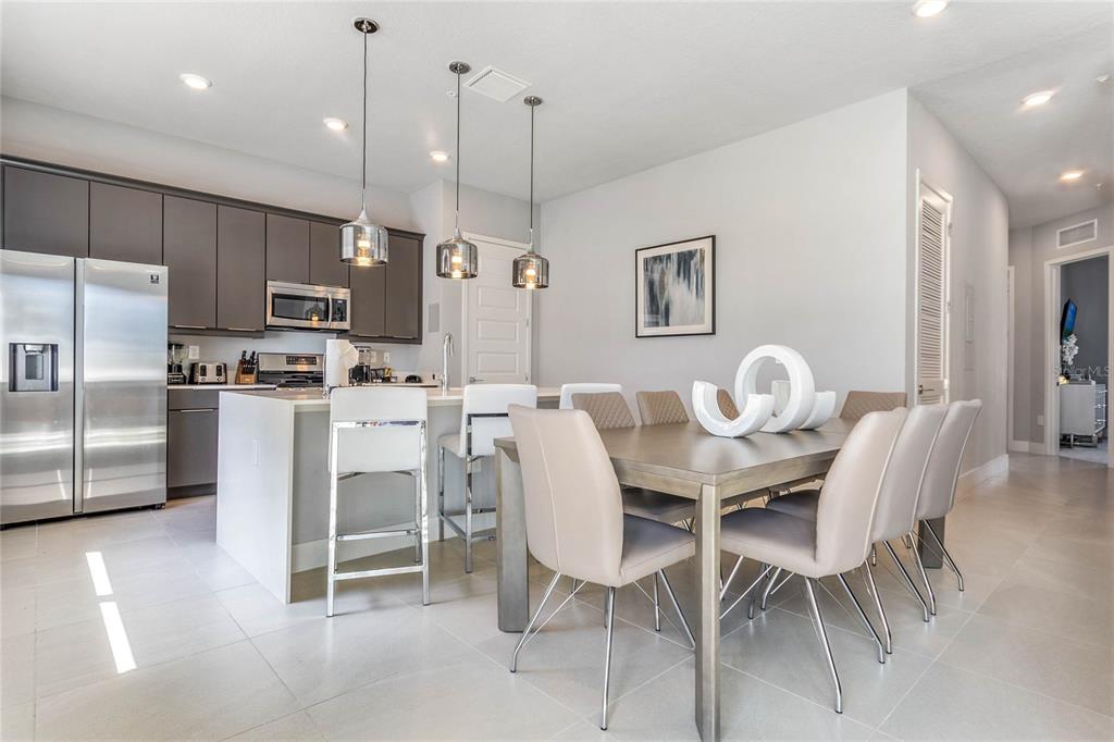 A modern kitchen and dining area features gray cabinetry, a white island, and neutral furniture — 7770 SANDY RIDGE DRIVE UNIT 112, REUNION, FL